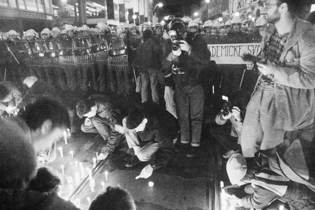 Lidé zapalují svíčky před policejním kordonem, který je násilím zastavil.
